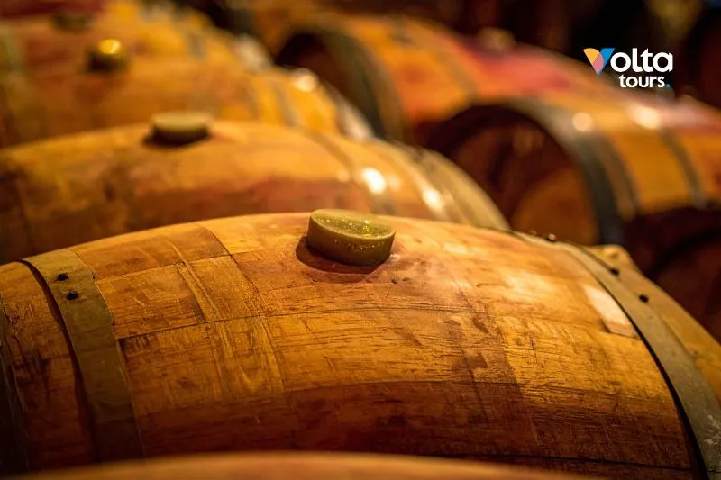 Barricas de roble tradicionales envejeciendo vino Bobal en una histórica bodega subterránea en Utiel-Requena